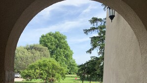 Un espace extérieur aménagé en terrasse, avec un sol en pierre, un grand bac à plantes et du mobilier d’extérieur.