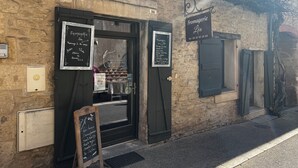 Un edificio in pietra con ingresso a cornice nera, una targa con il nome 'Fromagerie Léa' e un'ampia lavagna con il menu all'esterno.
