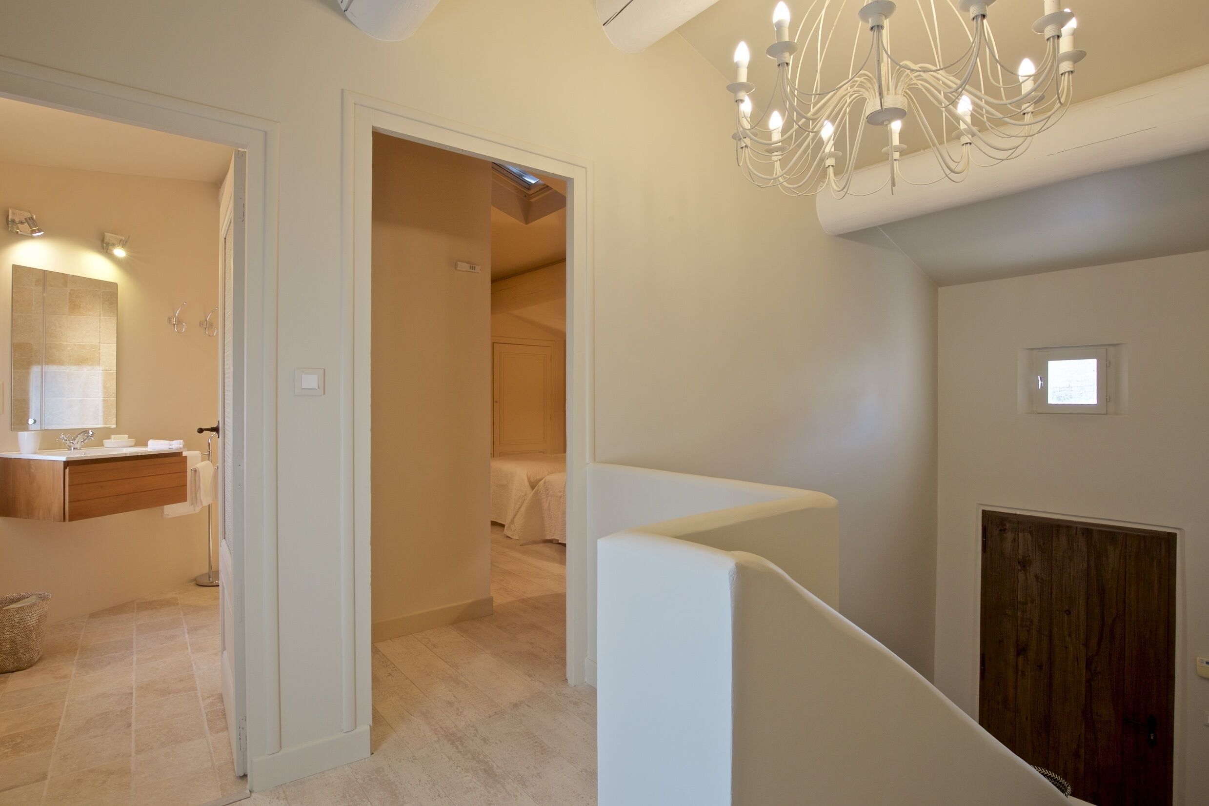 Une salle de bain moderne avec un lavabo, un miroir et un porte-serviettes. Un escalier mène à une autre pièce.