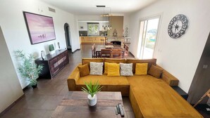 A modern living room with a large sectional sofa, a dining table, and a kitchen in the background. - Villa Angel - Panoramic view with magnificent swimming pool and pool house (La Gaude)