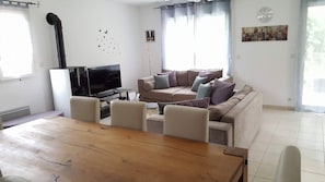 Un salon avec un canapé, un téléviseur et une table à manger.