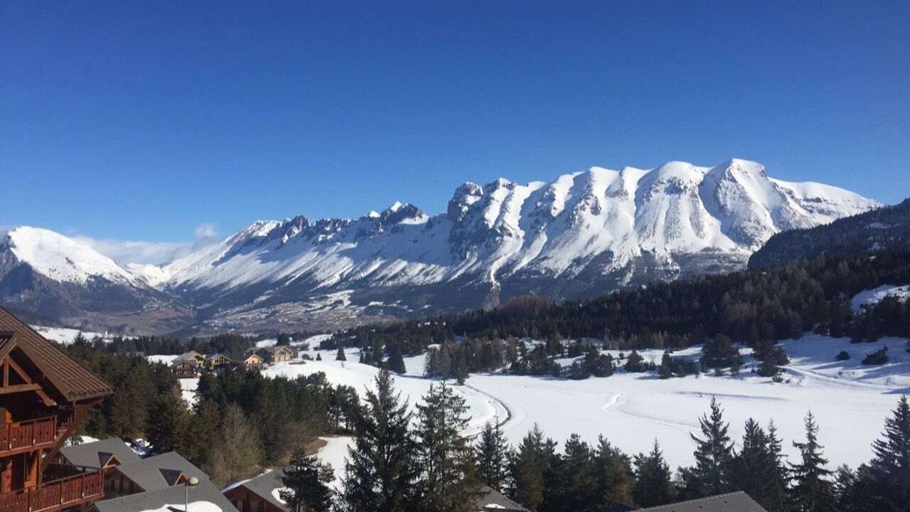 A snow-covered mountain landscape with a wooden cabin in the foreground.