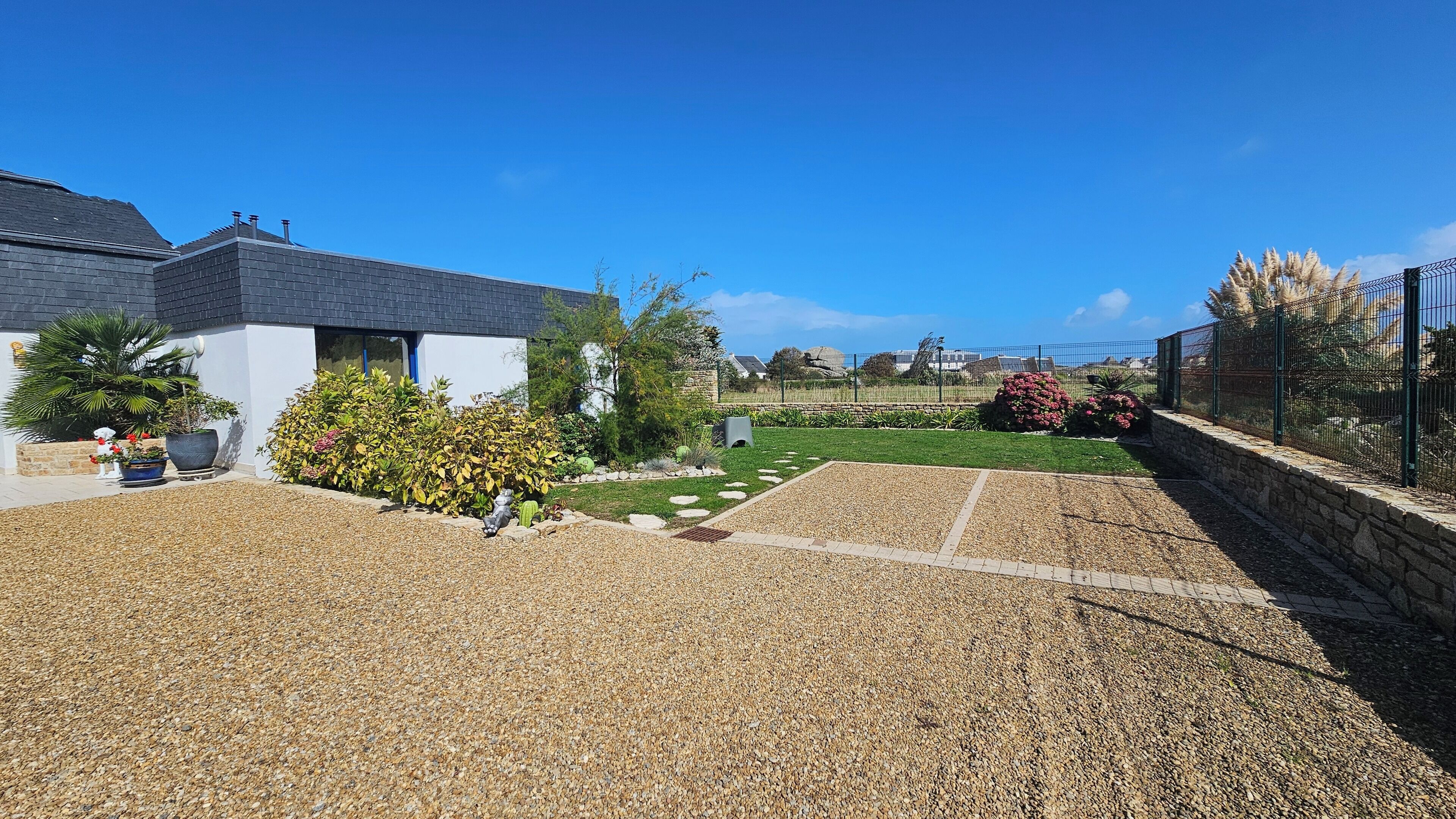 A residential property with a paved driveway, a lawn, and a stone wall.