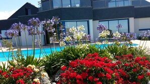 Un edificio moderno con piscina rodeada de flores y follaje exuberante.