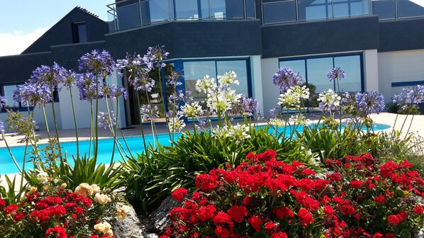 A modern building with a pool surrounded by vibrant flowers and greenery.