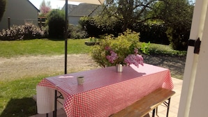 A table with a checkered tablecloth, a vase with flowers, and a bench.