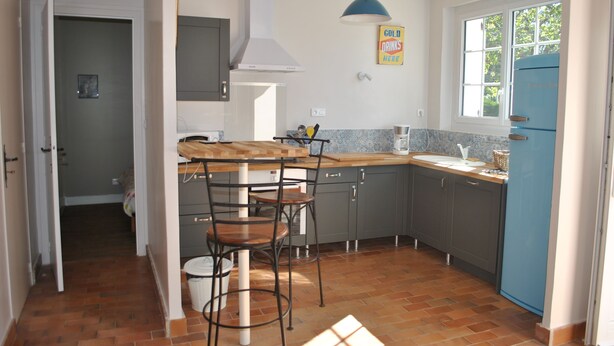 A compact kitchen with a wooden countertop, a blue refrigerator, and a window providing natural light.