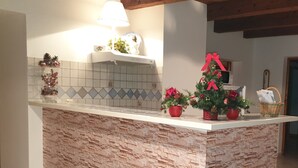 Une cuisine avec un îlot central à l’aspect pierre, une lampe et des décorations de Noël.