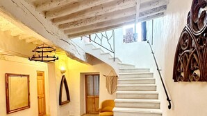 Un intérieur spacieux avec un escalier blanc menant à un deuxième étage, une porte en bois et un fauteuil jaune.