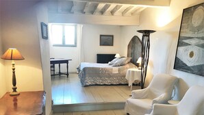 Une chambre à coucher avec un lit, deux chaises, une table et une lampe.