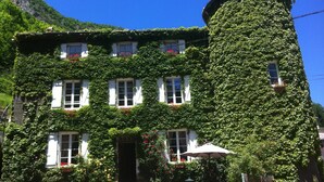 A building with a tower covered in ivy, white windows, and a stone staircase leading to the entrance. - Family Castle Life  (Mérial)