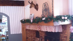 A cozy fireplace with a mantel decorated with greenery and a deer head. - Family Castle Life  (Mérial)