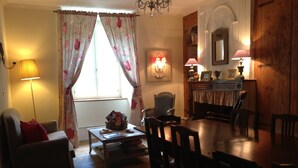 A cozy living room with a sofa, a coffee table, and a dining table set for four. - Family Castle Life  (Mérial)