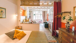 A bedroom with a bed, a dresser, a mirror, and a view into the dining area. - Charming studio 2 minutes from the Arena (Arles)