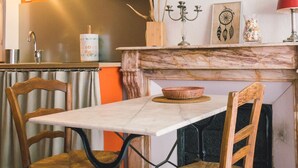 A cozy kitchen with a marble countertop, two wooden chairs, a patterned floor, and a red lamp. - Charming studio 2 minutes from the Arena (Arles)