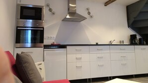 A modern kitchen with white cabinets, stainless steel appliances, and a built-in oven.
