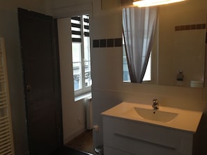 A bathroom with a white sink, a mirror, and a window with curtains. - Located in the inner city of Honfleur, with aspect of both town house and apt. (Honfleur)