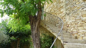 A stone staircase with a metal railing leading to a door, surrounded by lush greenery and a tree. - Large family home with character, south of France + independent studio apartment (Souvignargues)