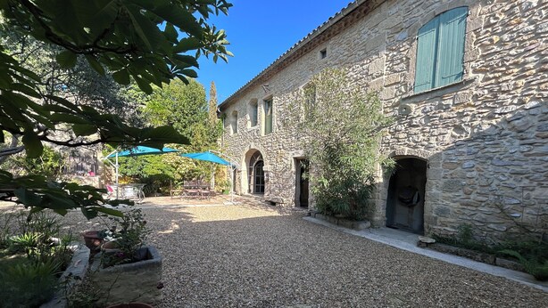 A courtyard with stone buildings, a gravel path, and potted plants. - Large family home with character, south of France + independent studio apartment (Souvignargues)