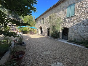 A courtyard with stone buildings, a gravel path, and potted plants.