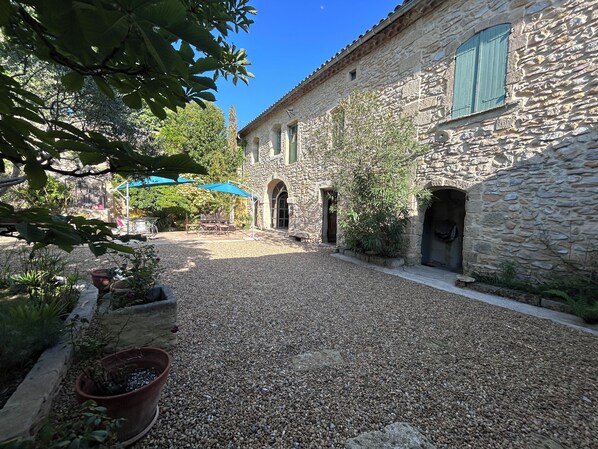 A courtyard with stone buildings, a gravel path, and potted plants.