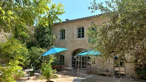 A stone building with a courtyard, outdoor seating, and potted plants. - Large family home with character, south of France + independent studio apartment (Souvignargues)
