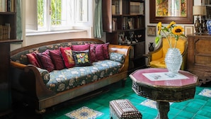 A room with a large window, a sofa, a bookshelf, and a decorative table.