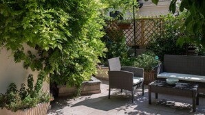 A patio area with a wicker sofa, a coffee table, and potted plants.