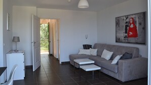 Ein modernes Wohnzimmer mit einem grauen Sofa, einem weißen Couchtisch und einem Schreibtisch mit einer Lampe.