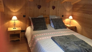 A cozy wooden room with a bed, two nightstands, and heart-shaped decorations on the wall.