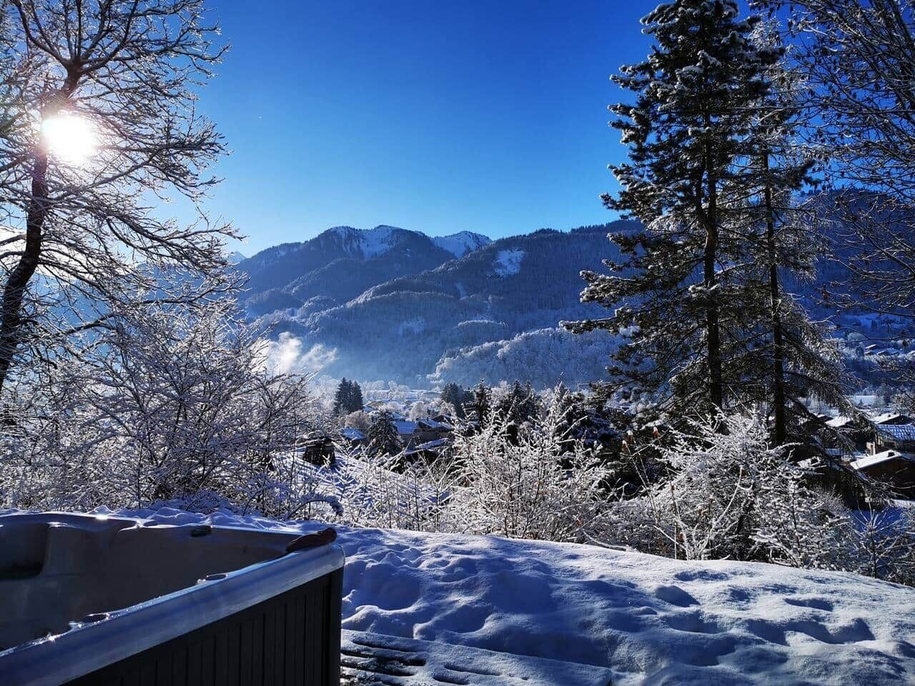 A snowy landscape with mountains in the background and a wooden deck in the foreground.