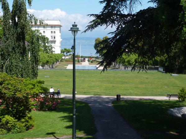 Un parc avec un chemin pavé, des bancs et un lampadaire.