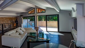 Una sala de estar moderna con un sofá blanco, una mesa de centro de vidrio y una pared de piedra.