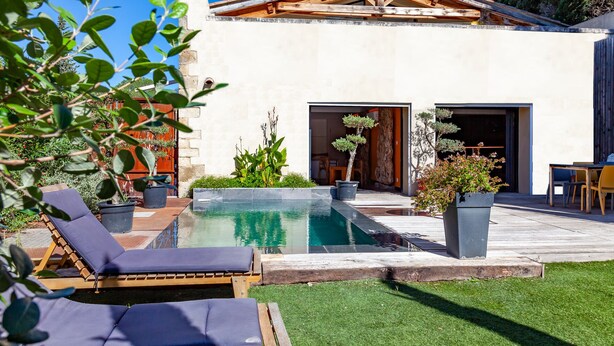 Una casa moderna con piscina, mobiliario exterior y un jardín bien cuidado.