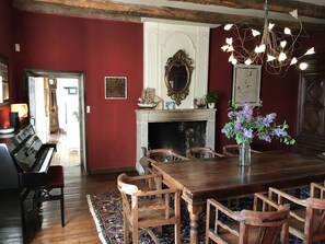 A dining area with a wooden table and chairs, a fireplace, a mirror, and a chandelier.