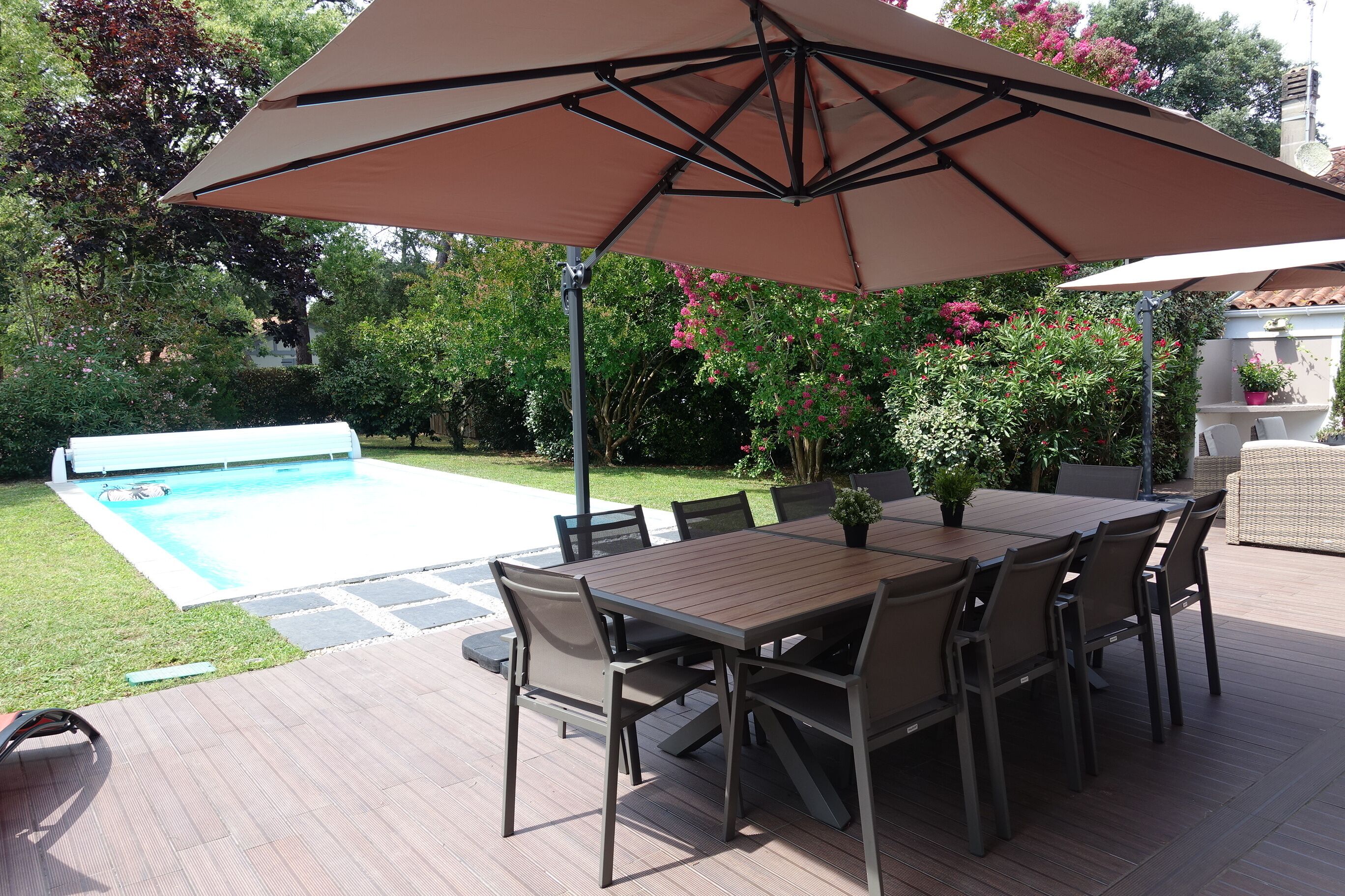 Patio con tavolo e sedie, piscina e vegetazione circostante.