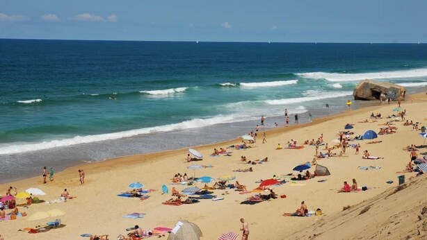 A crowded beach with people sunbathing and swimming, a large rock formation, and the ocean in the background. - Villa 600 m from the beach, heated swimming pool 9x4, classified 3*. (Labenne)