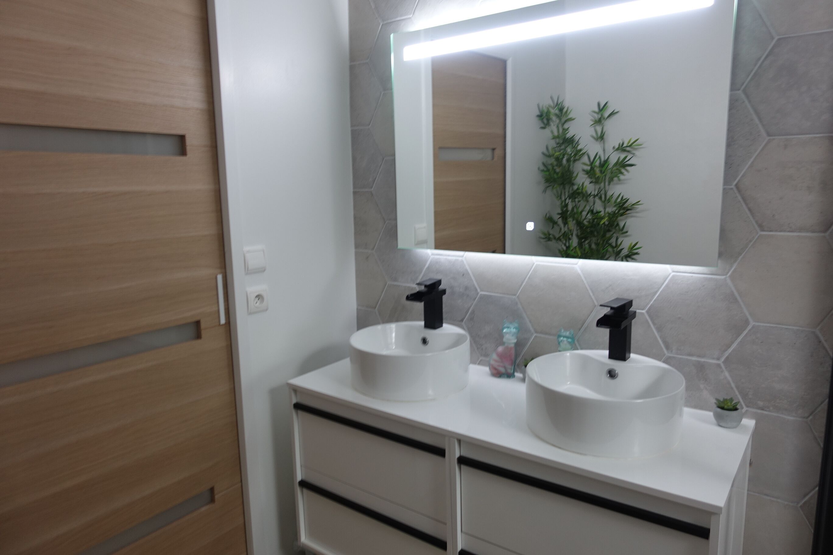 A bathroom with two sinks, a mirror, and a wooden door.