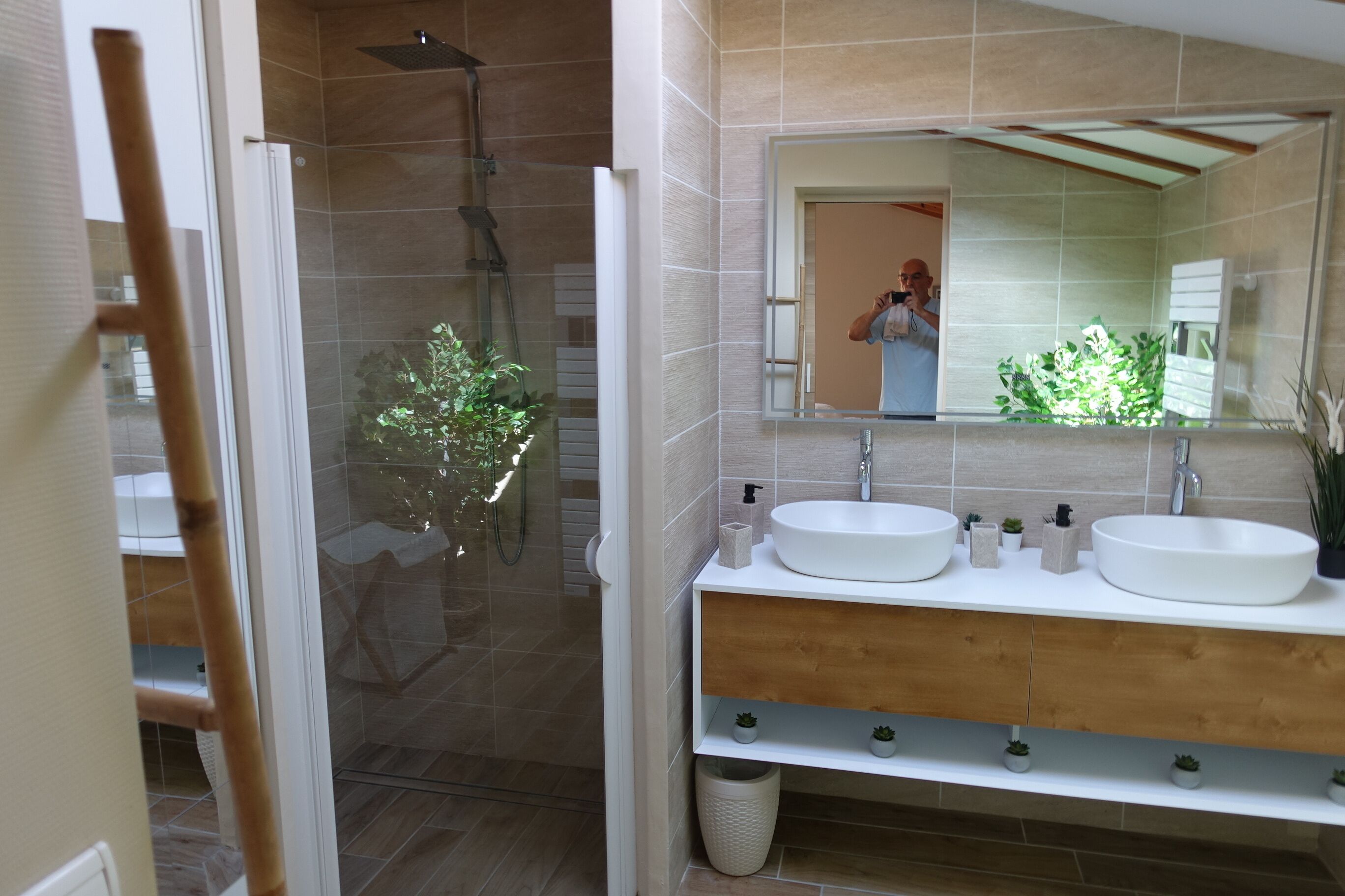 A modern bathroom with two sinks, a shower, and a mirror.