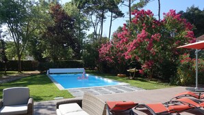 A backyard with a swimming pool, outdoor furniture, and lush greenery. - Villa 600 m from the beach, heated swimming pool 9x4, classified 3*. (Labenne)