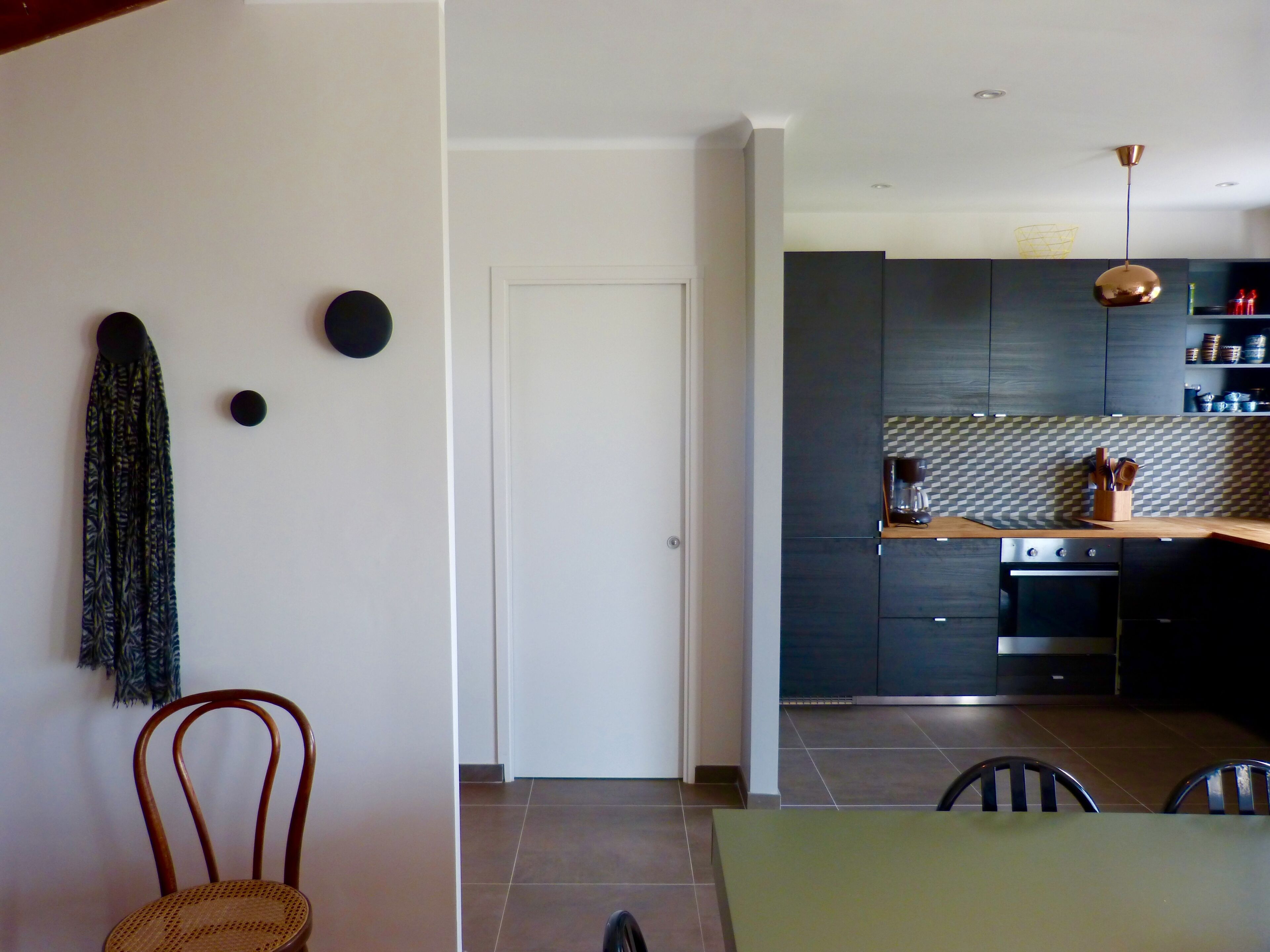 Una cocina moderna con armarios oscuros, una estufa de acero inoxidable y una lámpara colgante.
