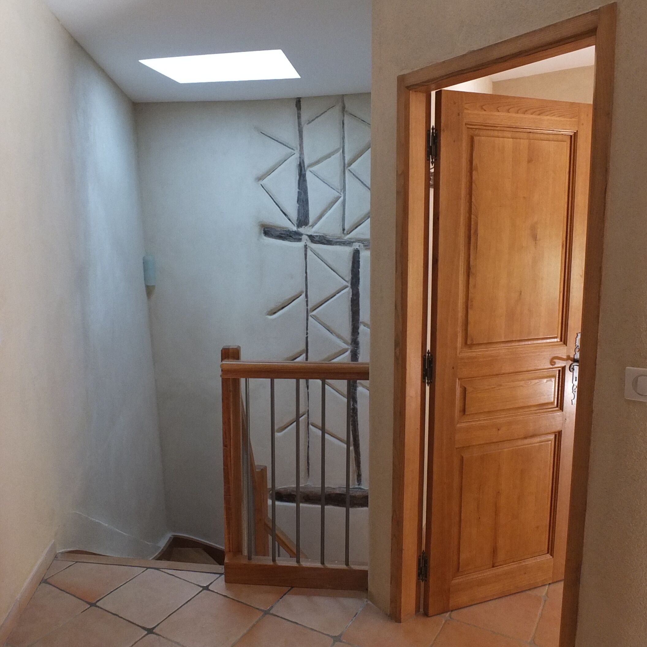 Un estrecho pasillo con una puerta de madera, una reja de metal y un tragaluz.