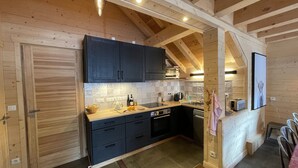 Une cuisine de taille réduite avec des meubles de couleur sombre, un plan de travail en bois et un revêtement mural en carreaux.