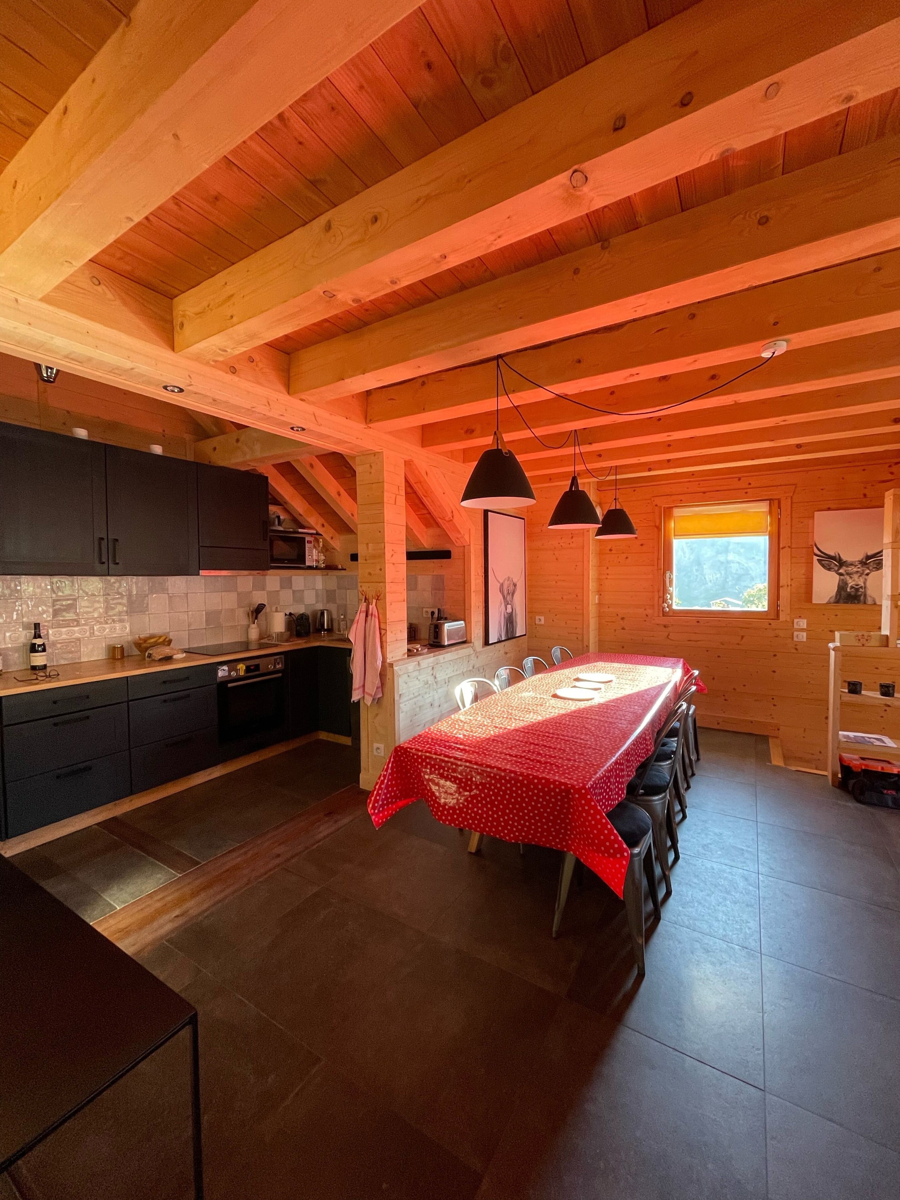 Una cocina amplia con una isla central grande, gabinetes oscuros e iluminación colgante.