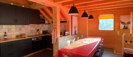 Una cocina amplia con una isla central grande, gabinetes oscuros e iluminación colgante.