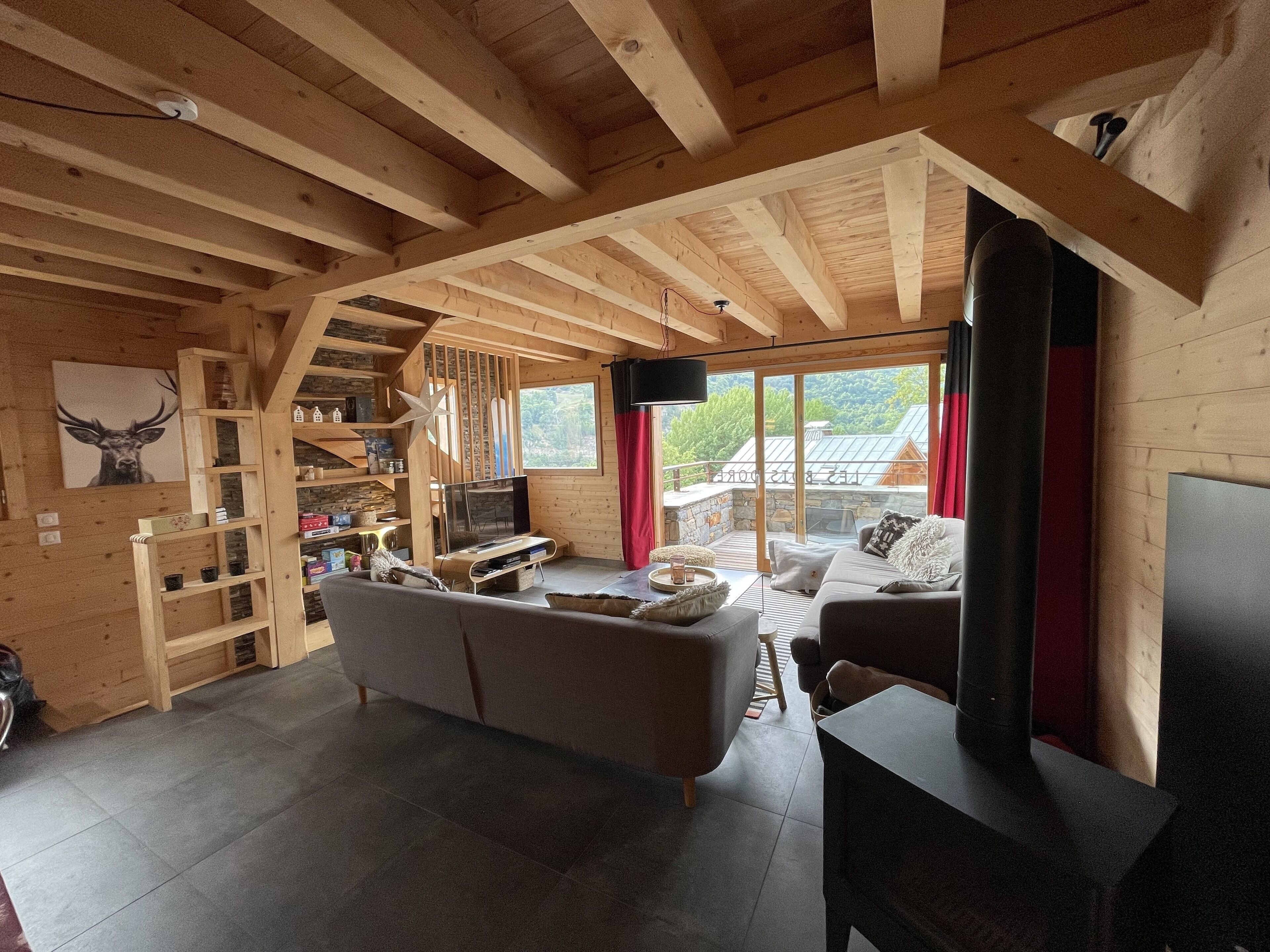 A cozy wooden interior with a sofa, TV, and a stone fireplace.