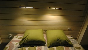Una stanza con pareti rivestite in legno, due cuscini verdi e un letto con copriletto decorato.