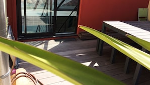 Un patio in legno con una porta scorrevole in vetro che dà su una zona esterna coperta.