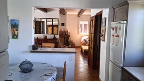 Una cocina con zona de comedor, refrigerador y ventana con cortinas.