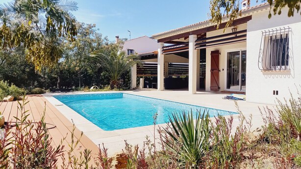 Una piscina con una pérgola y un patio cubierto.